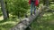 Woman with backpack walking in forest area balancing on a trunk