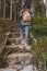 woman with backpack walking by stone stairs leads to the forest