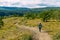 Woman with backpack walks along footpath with mountain