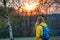 Woman with backpack and yellow jacket hiking in forest during sunset