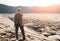 Woman with backpacker enjoying sunrise at desert canyon.