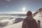 Woman backpacker hiker looking at view high up on the Alps. Rear view, winter cold snow, sun star in backlight, split toning, desa