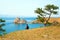 A woman backpacker looks at the Shamanka Rock, Cape Burhan on Olkhon Island. Lake Baikal, Russia.