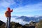 Woman backpacker taking selfie on mountain peak cliff edge