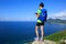 Woman backpacker use digital tablet on seaside mountain rock