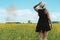 Woman backwards wearing dress and hat on a beautiful yellow field full of flowers