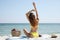 Woman with bag and other beach stuff on sand near sea, back view