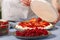 woman baker add a new layer of meringue base in strawberry cake. Homemade strawberries cake made from meringue cake and