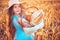 Woman baker or girl farmer holding wicker basket with homemade bread in organic wheat field. Healthy food and agriculture concept