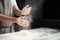 Woman baker sprinkled flour on roll dough on a wooden board. Pro