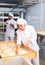 Woman baker sprinkles from spray bottle on raw dough in the kitchen at bakery