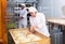 Woman baker sprinkles from spray bottle on raw dough in the kitchen at bakery