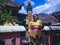 Woman With Balinese Traditional Clothing Bring Offerings On A Small Balinese House Shrines In A Holiday
