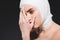 Woman with bandaged head covering face isolated on grey