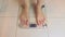 Woman bare feet standing on the scales and weighed in the bathroom, the scales show 67,4 kg - diet and weight loss