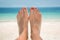 Woman bare sandy feet, beach and sea