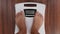 Woman barefoot legs stepping on floor scales for weighing. Weight loss