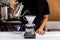 Woman barista making pour-over coffee with alternative method called Dripping. Coffee grinder, coffee stand and pour-over.