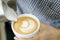 Woman barista pouring stream milk for making latte art coffee with heart shape in white cup, selective and soft focus