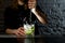 Woman barman making alcoholic cocktail and squeezing juice in glass which splashing out