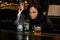 Woman bartender gently pours drink to glass with ice.