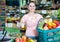 woman with basket with fresh greengrocery enjoying purchases in vegetable store