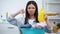 Woman with basket full of clothes and laundry detergent showing thumbs-down