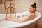 Woman in bath with rose petals and foam