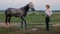 woman bathes the horse, washes and takes care of. Water from the hose pours on the horse. Bathing after training, the