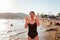 A woman in a bathing suit screams from sunburn. Redness on the skin of the face and body. In the background, the beach and the sea