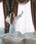 Woman in bathrobe stay near the window in hotel room.