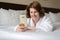 A woman in bathrobe wears telephone in hotel room