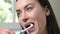 Woman In Bathroom Brushing Teeth With Electric Toothbrush