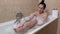 Woman in bathtub with sponge washing feet