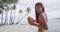 Woman on beach in bikini drinking from coconut walking on beach having fun