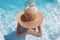 Woman in beach hat enjoying in swimming pool on luxury tropical