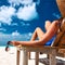 Woman at beach holding sunglasses