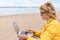 A woman on the beach with a laptop studying the news