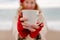 Woman beach in red beret scarf and mitts holding a cup of tea in his hands. Depicting beach relaxation and cozy attire