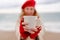 Woman beach in red beret scarf and mitts holding a cup of tea in his hands. Depicting beach relaxation and cozy attire