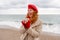 Woman beach in red beret scarf and mitts holding a cup of tea in his hands. Depicting beach relaxation and cozy attire