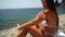 Woman beach sea. Women's legs by the sea and women's hands are smeared with sunscreen. Slow motion video of a