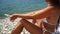 Woman beach sea. Women's legs by the sea and women's hands are smeared with sunscreen. Slow motion video of a