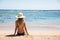 Woman on beach sitting in sand looking at ocean enjoying sun and summer travel holidays vacation getaway. Girl in bikini relaxing