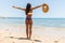 Woman on Beach standing with arms outstretched against turquoise sea. Rear view of female wearing bikini with raised hands. Carefr