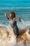 Woman on the beach surprised by a wave, splashed, concept holiday