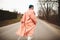 A woman in a beautiful coat and white dress rides along the way. Back viev
