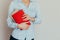 Woman with beautiful curmi holds a closed red book or magazine in a room against a light wall