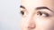 Woman with beautiful eyebrows close-up on a light background with copy space. Microblading, microshading, eyebrow tattoo, henna,