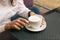 Woman with beautiful hands is drinking coffee in cafe. Close-up cappuccino in white cup, image with author processing.